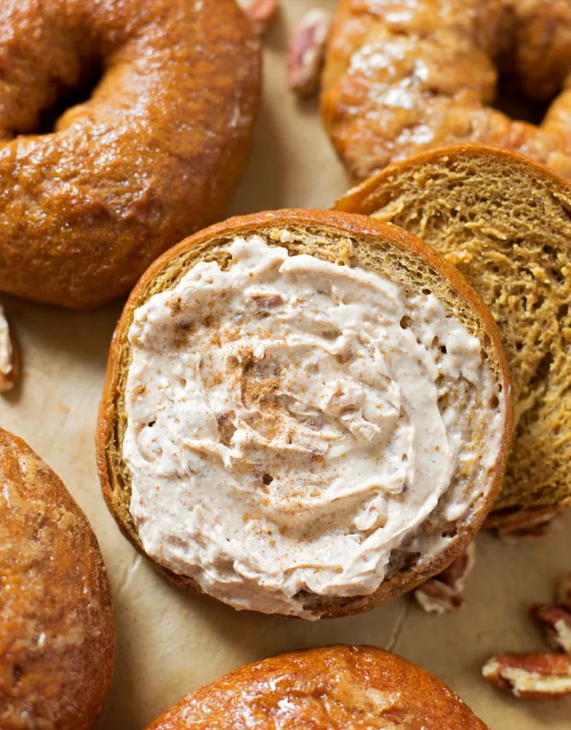 pumpkin bagels with one cut in half with cream cheese