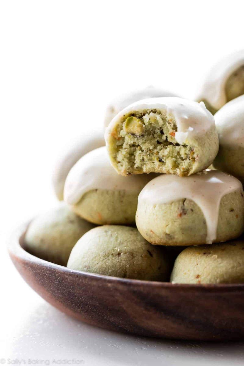 pistachio cookies stacked in bowl with one cut open
