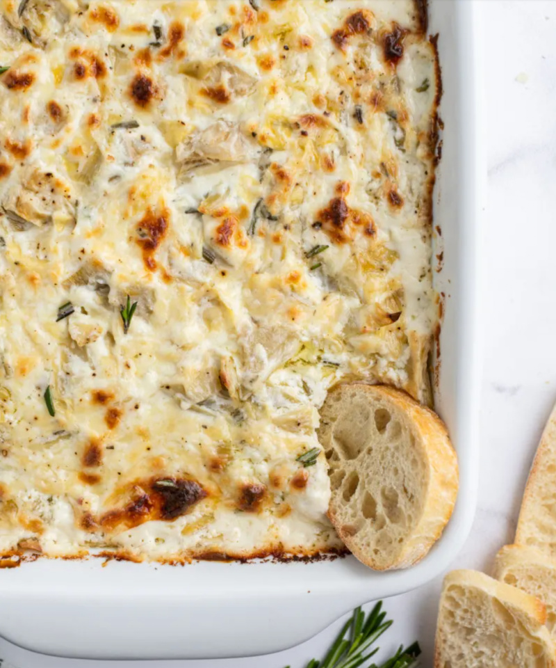 cheesy lemon rosemary artichoke dip in dish