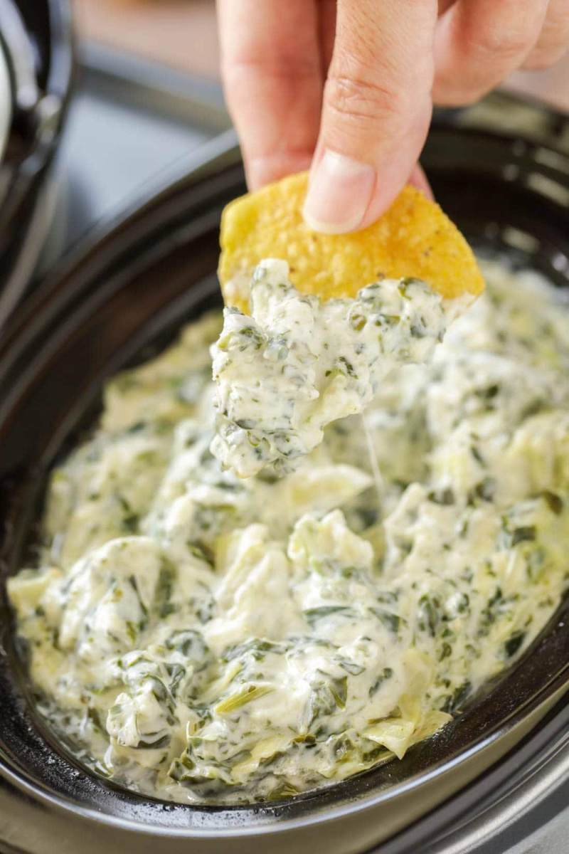 chip dipped into crockpot spinach artichoke dip