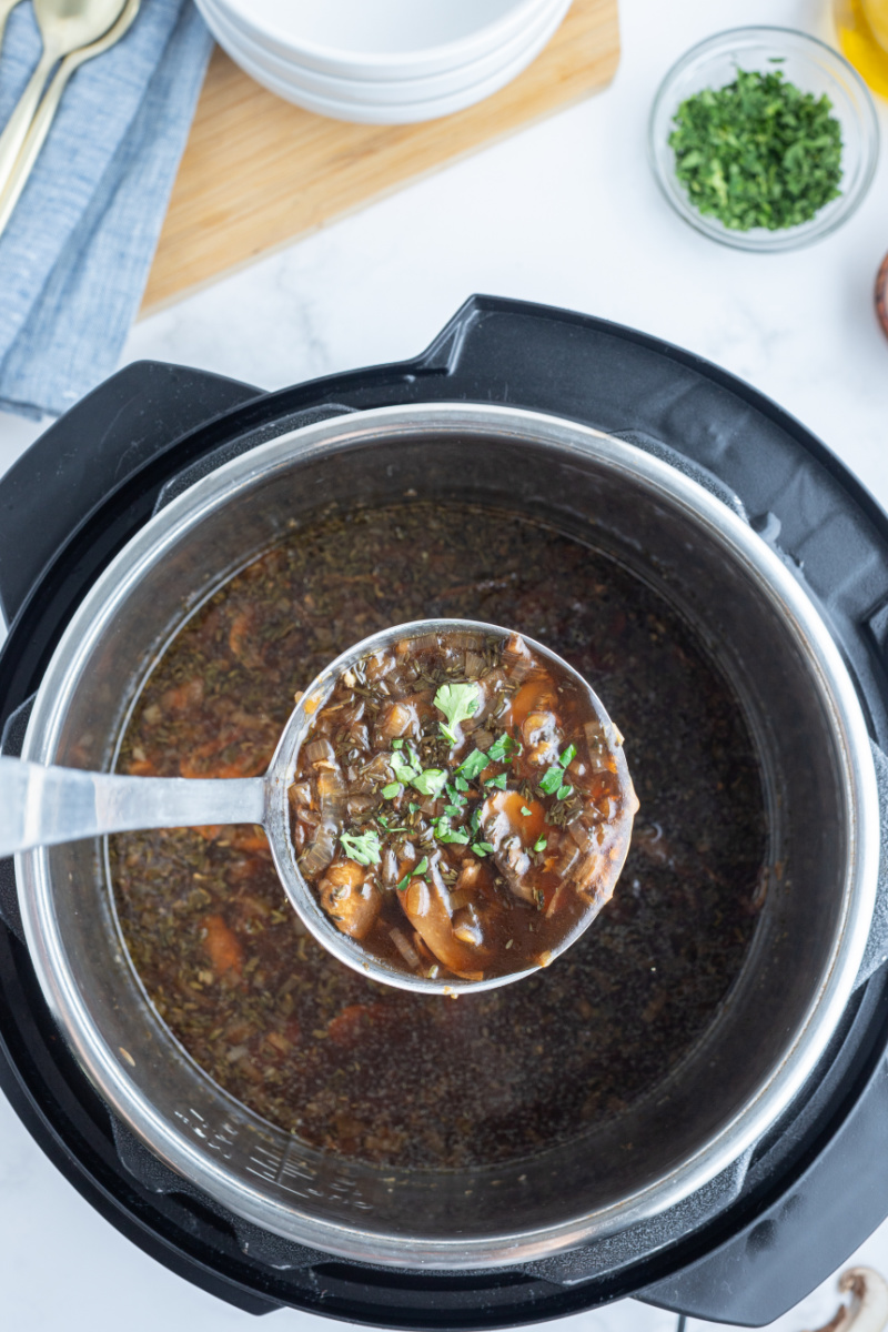 ladle full of wild mushroom soup set over instant pot