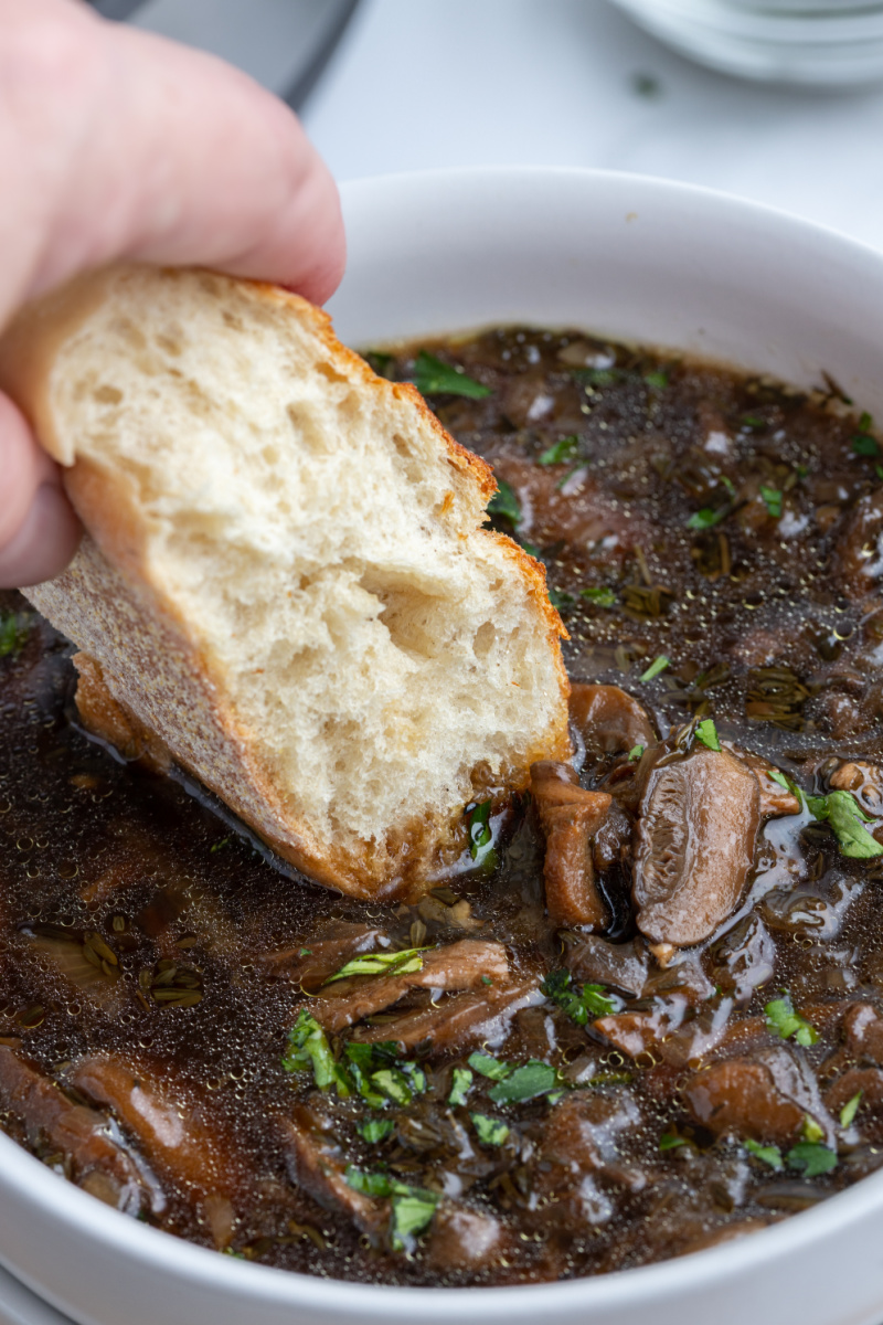 dipping bread into bowl of wild mushroom soup