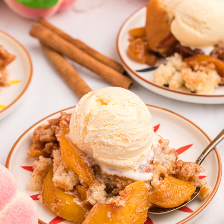 serving of peach cobbler on plate with scoop of vanilla ice cream on top