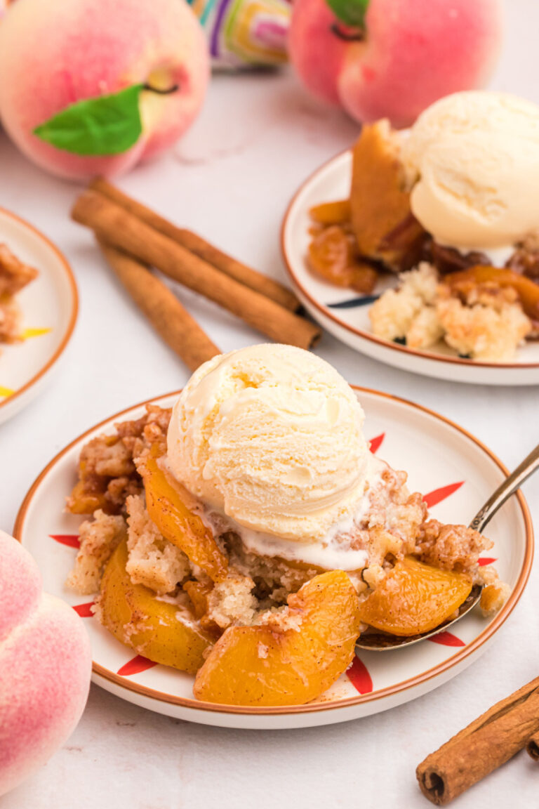 serving of peach cobbler on plate with scoop of vanilla ice cream on top