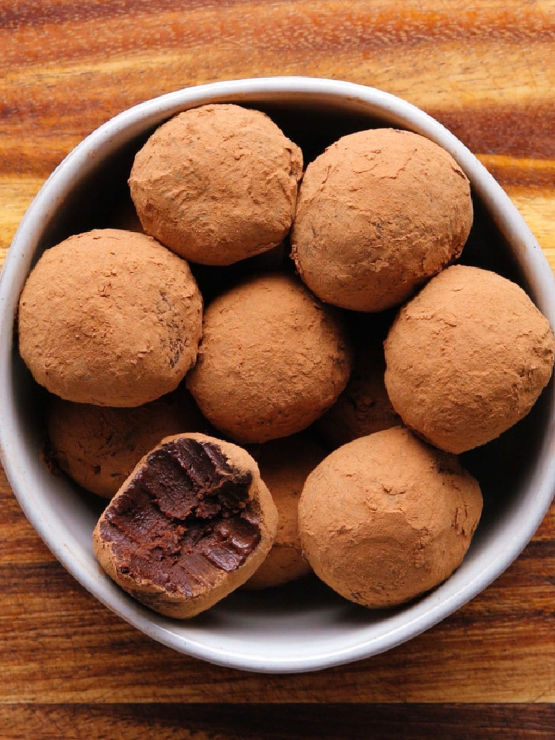 dark chocolate truffles in bowl with one bitten into