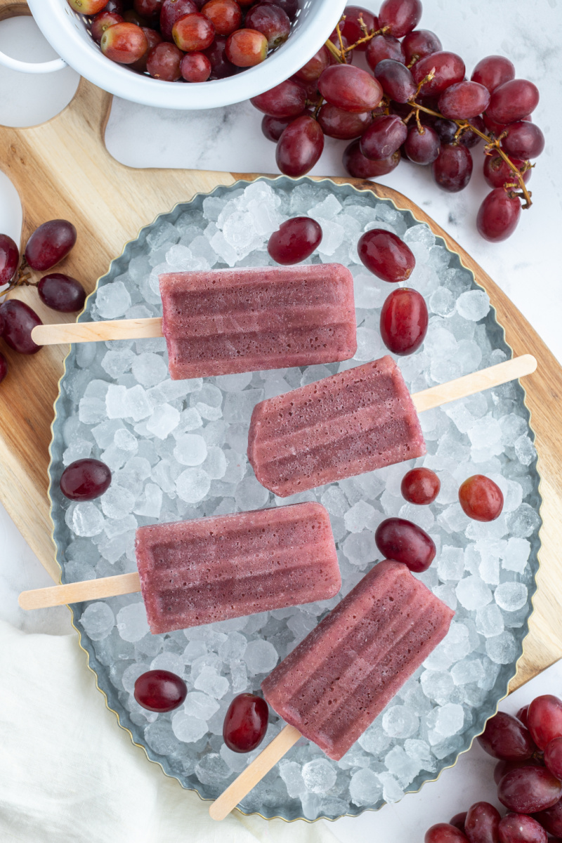 four grape popsicles placed in a bowl of ice