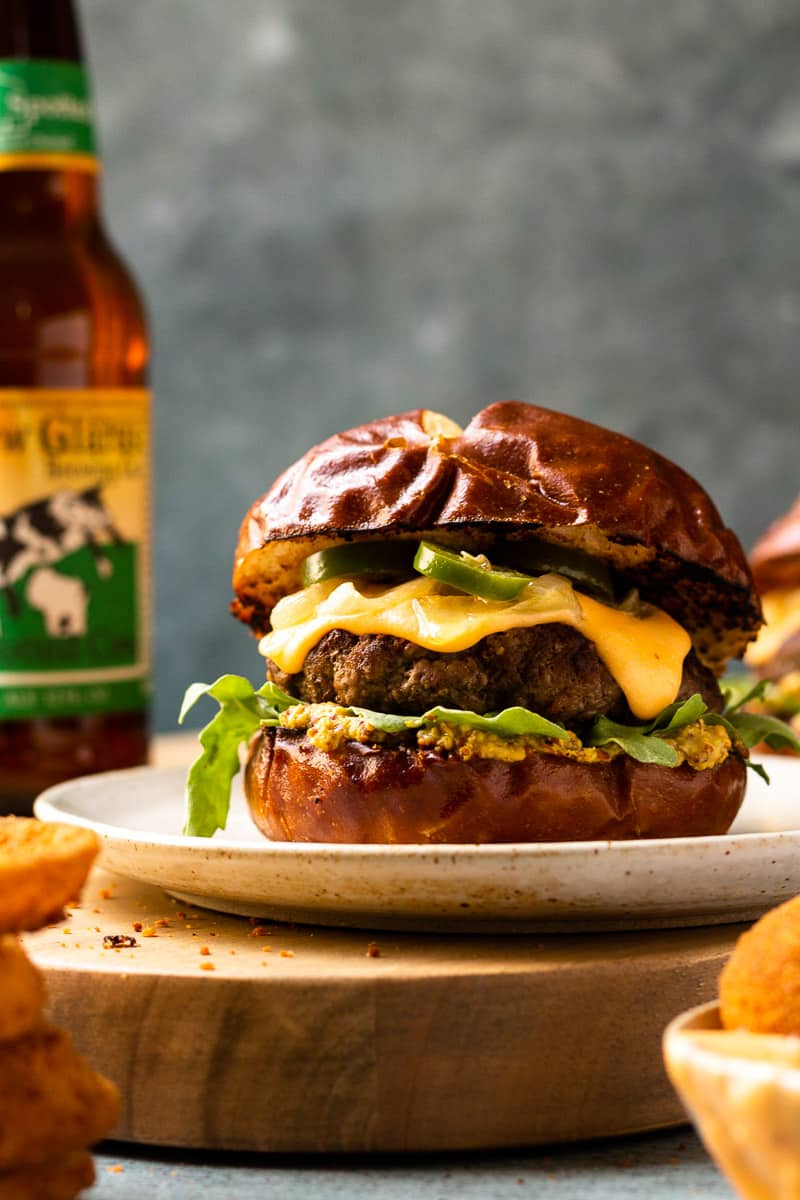 beer cheese burger on plate with bottle of beer in background