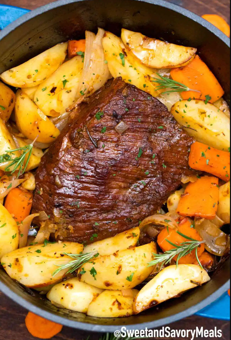 beer pot roast in a pan surrounded by veggies