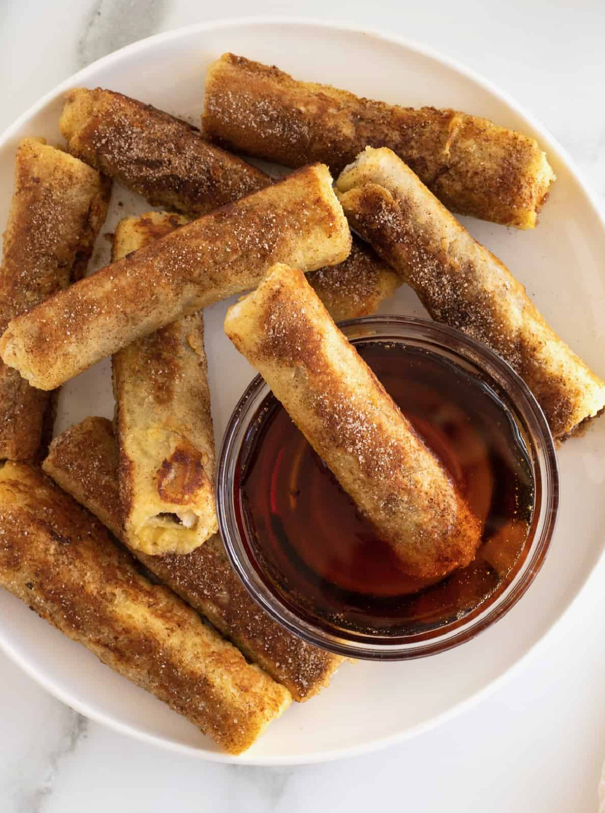 french toast roll ups with bowl of syrup