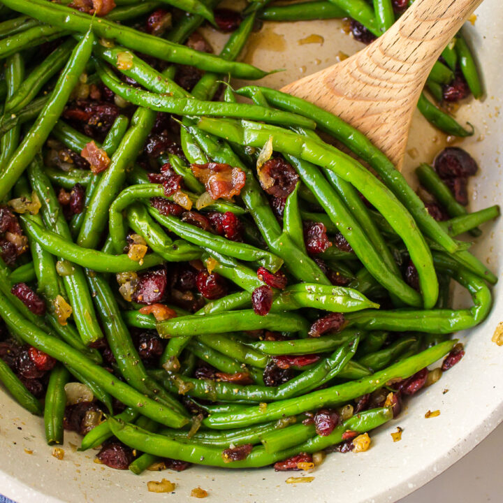 maple bourbon green beans in a pan with wooden spoon