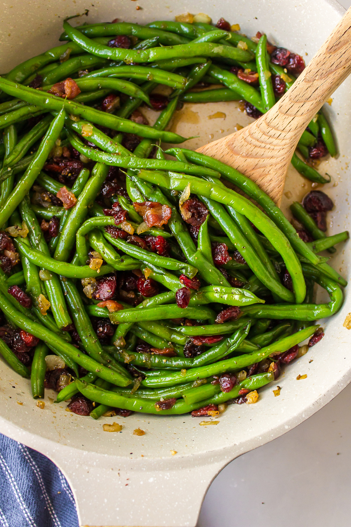 maple bourbon green beans in a pan with wooden spoon