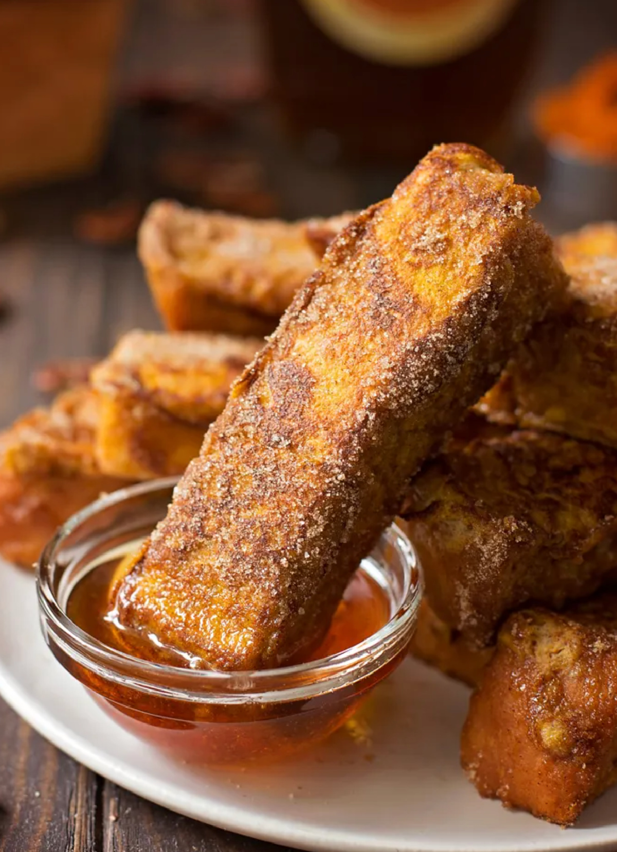 pumpkin french toast sticks inside bowl of syrup