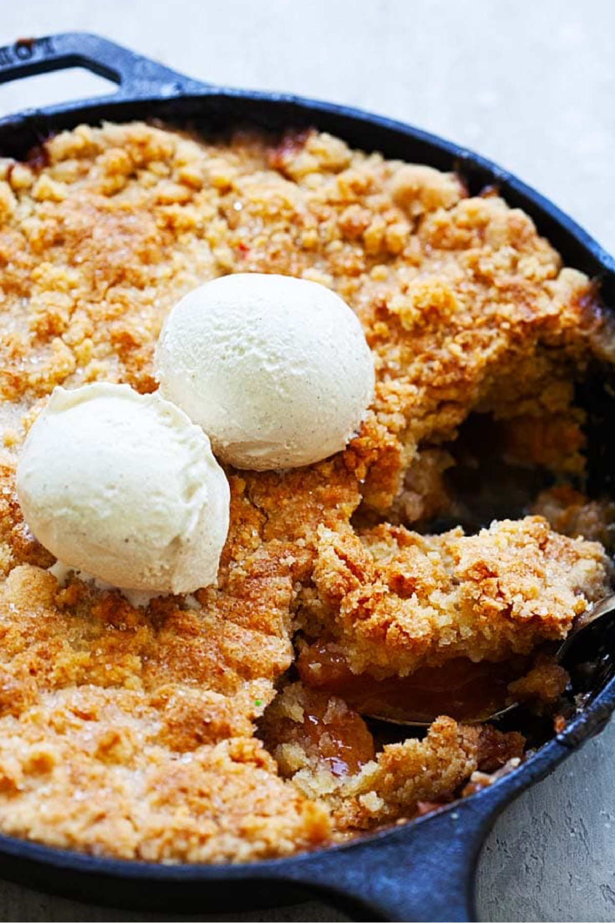 bourbon peach cobbler in skillet with ice cream scoops on top
