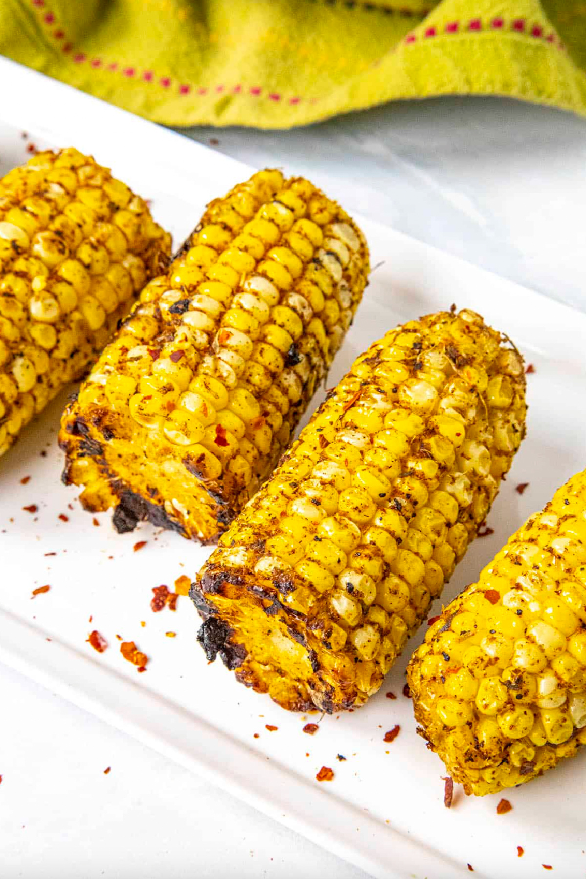 several jerk rubbed grilled corn on the cob on white platter