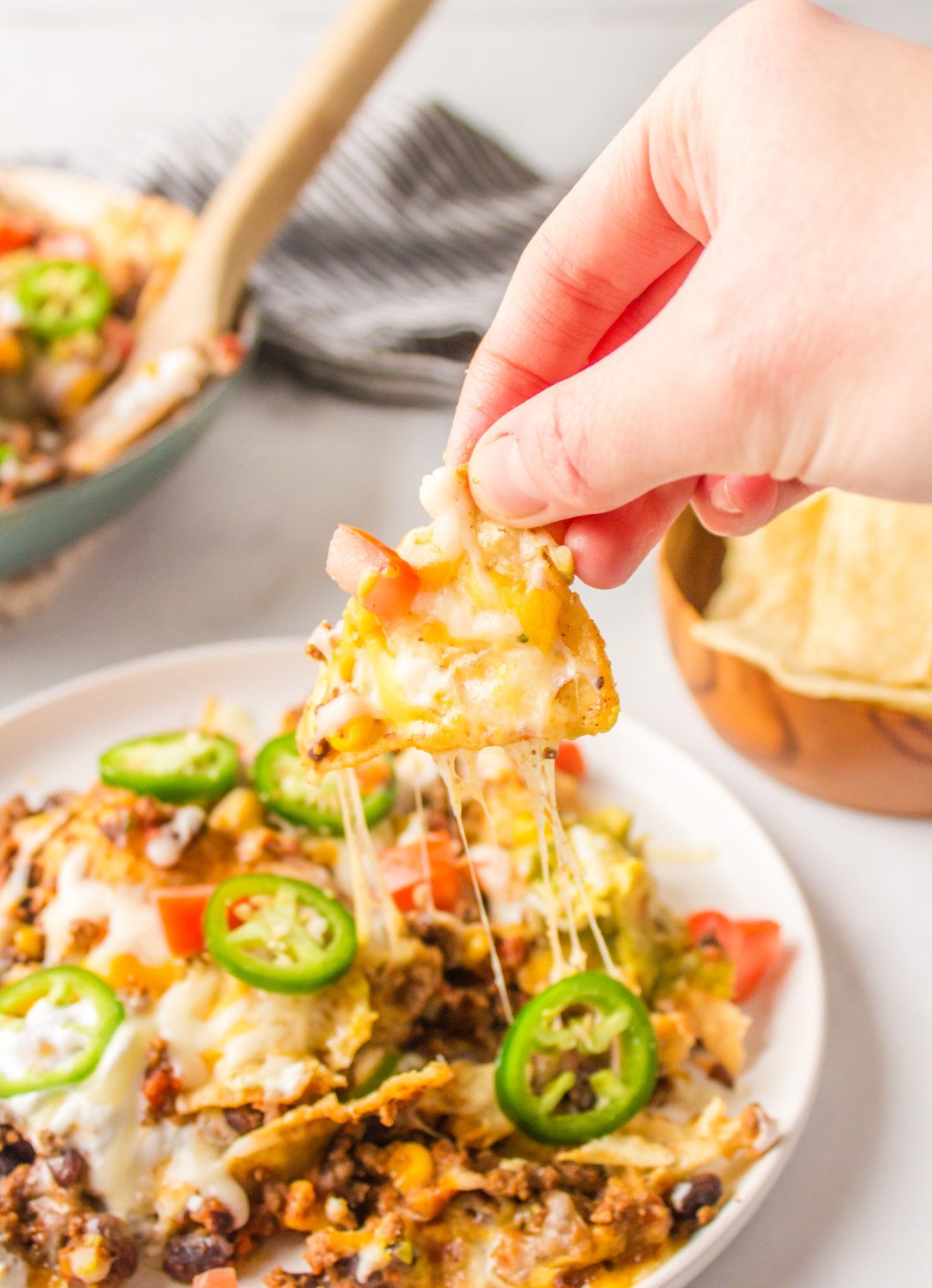 hand pulling nacho off plate