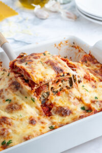 spatula pulling up a piece of spinach artichoke lasagna out of pan