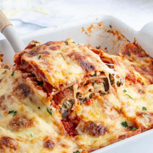 spatula pulling up a piece of spinach artichoke lasagna out of pan