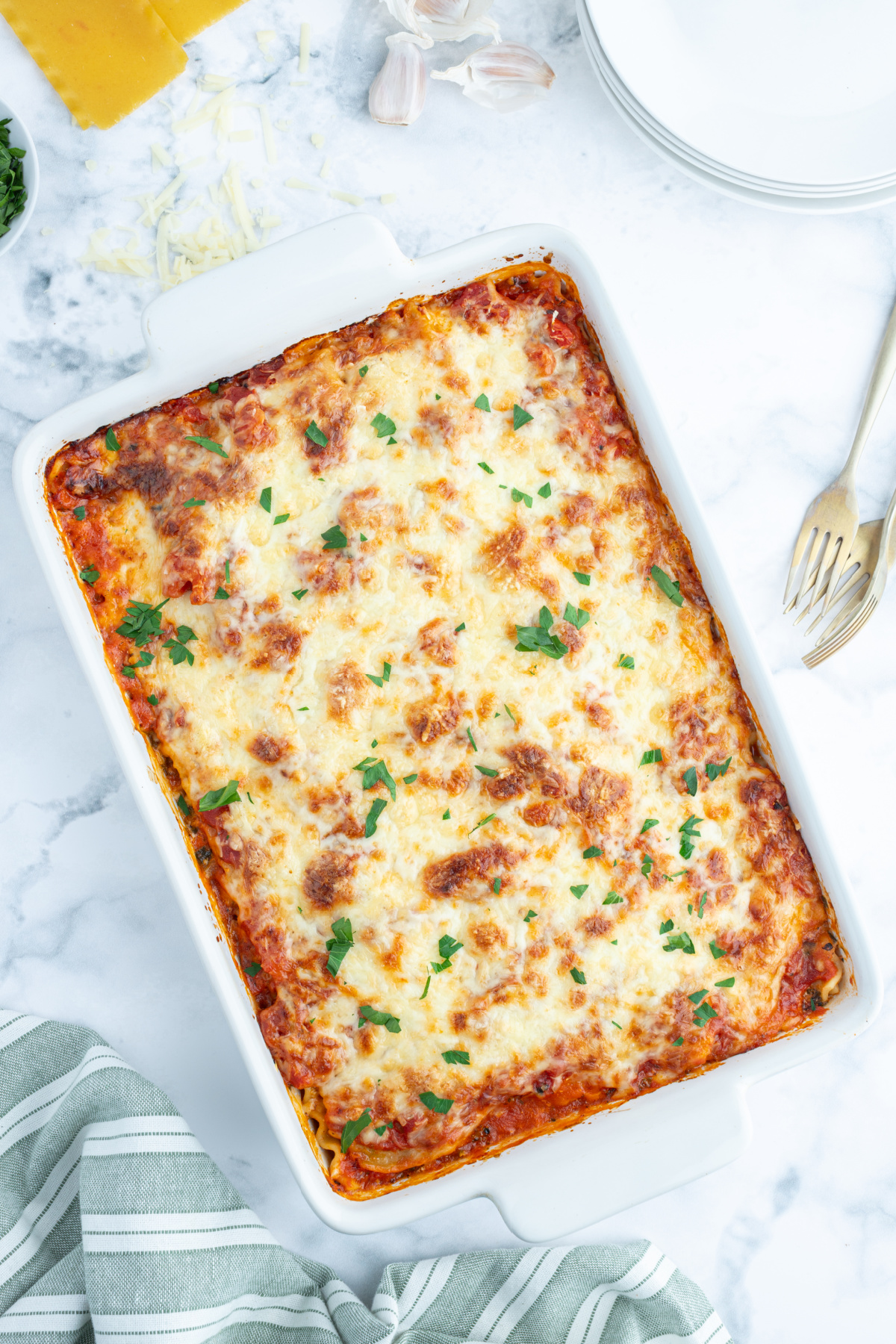 overhead shot of spinach artichoke lasagna in white baking dish